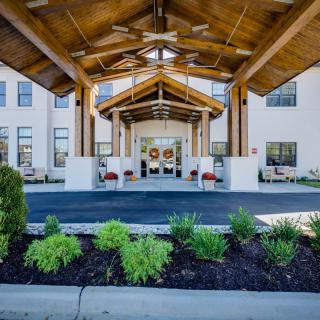 A modern building entrance with a wooden canopy and landscaped front.