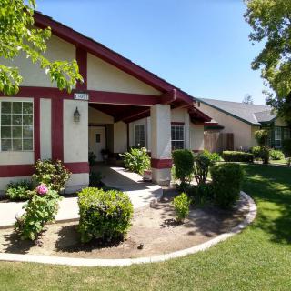 A charming residential house with well-maintained landscaping on a sunny day.