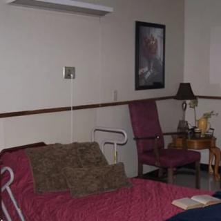 A hospital room featuring a bed, chair, and decorative elements.