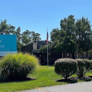 A sunny day at a facility with well-kept landscaping and an American flag.