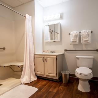 A clean and well-organized bathroom with a shower, toilet, sink, and mirror.