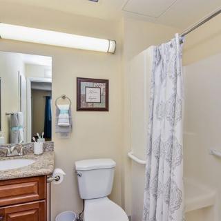 A clean and well-organized bathroom with a shower, toilet, sink, and mirror.
