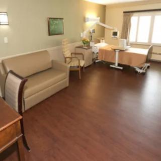 A clean and spacious hospital room with a patient bed and sofa.