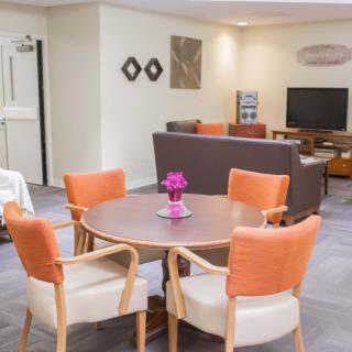 A cozy living room with a modern dining table and chairs, a television, and tasteful decor.