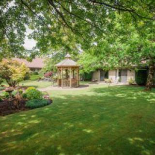 A tranquil garden with a gazebo surrounded by lush greenery and a well-maintained lawn.