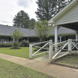A suburban house with a yard, trees, and a white fence.