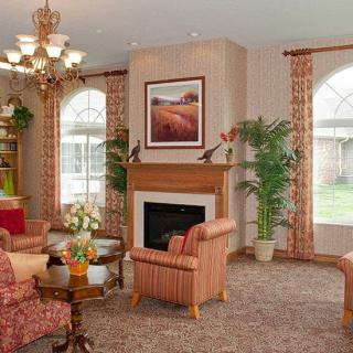 A cozy living room interior with warm tones, featuring a fireplace, comfortable seating, and natural light from large windows.