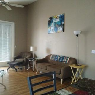 A cozy living room with a sofa, lamp, and artwork on the wall.