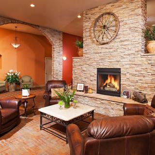 A cozy living room with a stone wall fireplace and leather seating.