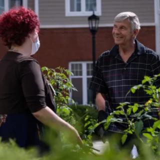 Two people having a conversation in a garden setting.