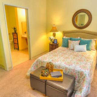 A cozy bedroom with a neatly made bed, decorative pillows, and a bedside lamp.