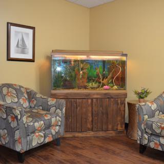 A cozy corner featuring a decorative aquarium and comfortable floral chairs.