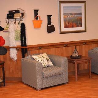 A cozy living room with armchairs, wall art, and decorative items on shelves.