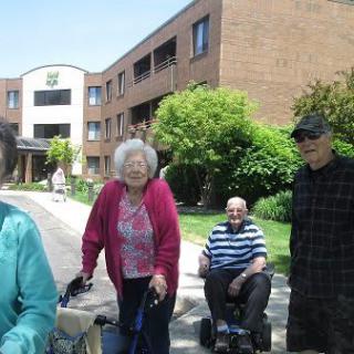 A group of seniors enjoying a sunny day outside near a residential building.