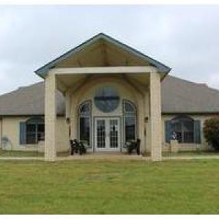 A wide view of a building with an entrance canopy and surrounding lawn.