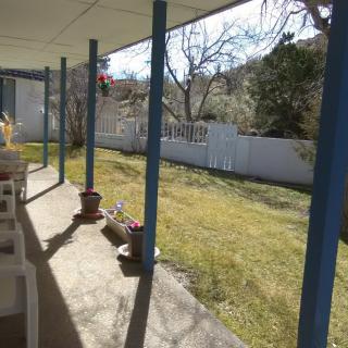 A sunny backyard with a covered patio and a fenced lawn area.