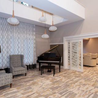A modern living room featuring a grand piano, elegant armchairs, and stylish pendant lights.