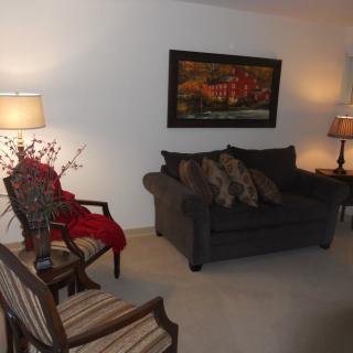 A cozy living room with a sofa, armchair, and warm lighting.