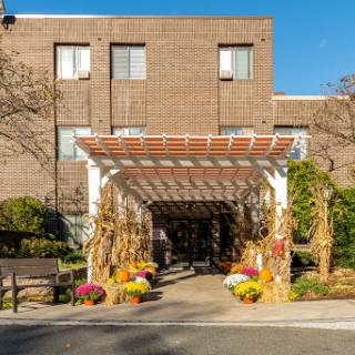 A beautifully decorated entrance featuring a pergola adorned with flowers, welcoming visitors on a sunny day.