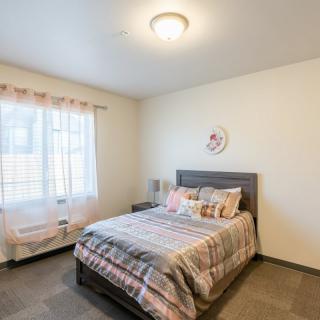 A cozy bedroom with a neatly made bed and natural light streaming through the window.