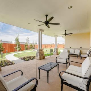 Spacious patio with comfortable seating and ceiling fans overlooking a landscaped yard.