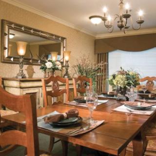 A beautifully set dining room with a wooden table, elegant chairs, and a chandelier.