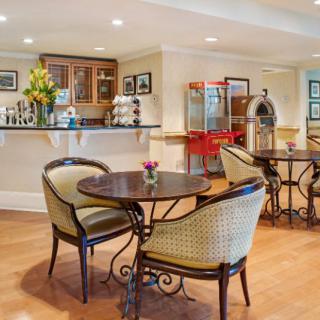A charming cafe interior featuring a mix of retro decor with a popcorn machine and jukebox, elegant tables and chairs for seating.