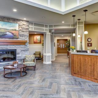 A modern lobby area with a reception desk and seating near a fireplace.