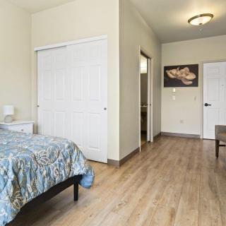 A spacious bedroom with wooden flooring and minimalist decor.
