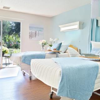A bright and clean hospital room with two beds and a view of the outdoors.