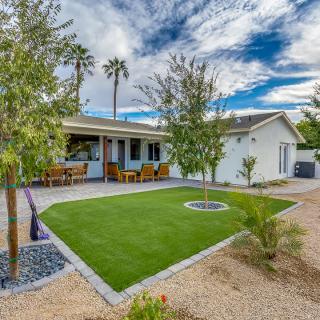 A cozy house with a landscaped yard, featuring a small patio and lush greenery under a partly cloudy sky.