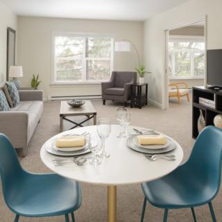 A modern, cozy apartment living room with a small dining area, featuring contemporary furniture and neutral tones.