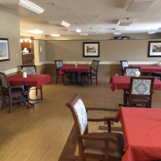 An empty dining room with red tablecloths and neatly arranged chairs.