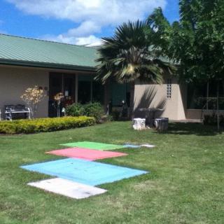 Canvas artworks drying on the lawn in a sunny backyard.