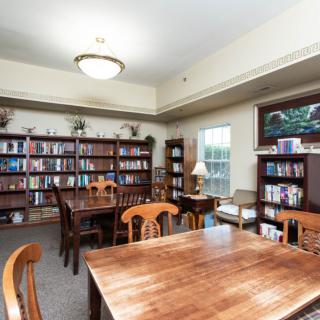 A cozy library reading room with wooden tables and bookshelves filled with books.