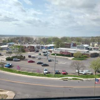 A panoramic view of a bustling suburban commercial area with cars parked in the lot under a cloudy sky.