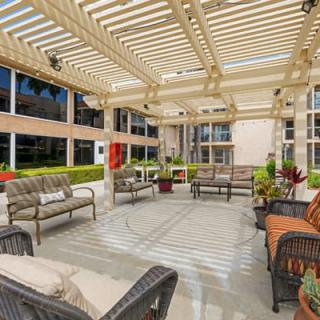 A modern outdoor patio with stylish seating under a pergola.