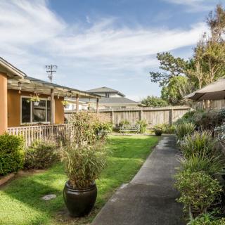 A view of a residential backyard featuring a well-maintained garden and a concrete pathway.
