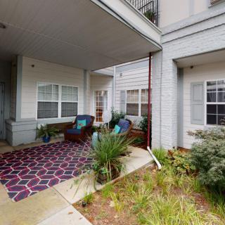 A cozy outdoor patio area with seating and plants at an apartment complex.