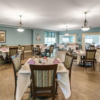 A spacious dining area with neatly arranged tables and chairs, well-lit by overhead lights.