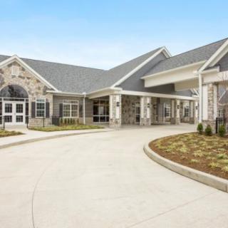 A modern building with a spacious driveway and landscaped surroundings.