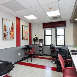 A modern hair salon interior with red accents, featuring chairs and workstations.