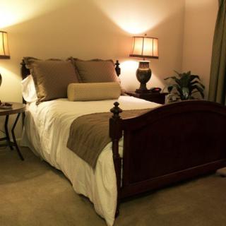 A cozy bedroom with a neatly made bed, warm lighting, and elegant decor.
