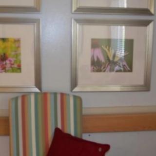 A cozy interior space featuring framed artwork and a striped chair with a red pillow.