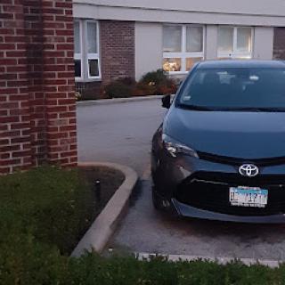 A black Toyota sedan parked beside a building.