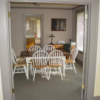 A dining room with a wooden table and eight white chairs.