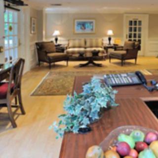 A cozy and well-decorated living room featuring a sofa set, a central table, and decorative items like a fruit bowl and plants.