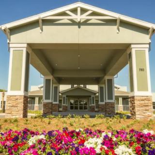 A covered building entrance with colorful flowers in the foreground.
