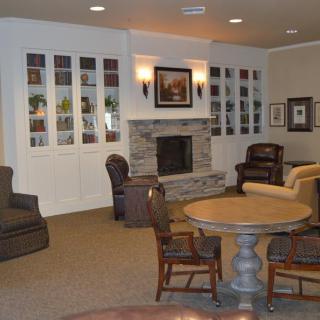 A cozy living room with a fireplace, surrounded by comfortable seating and bookshelves.