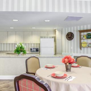 A well-decorated dining area with a table set for a meal and a view into the kitchen.